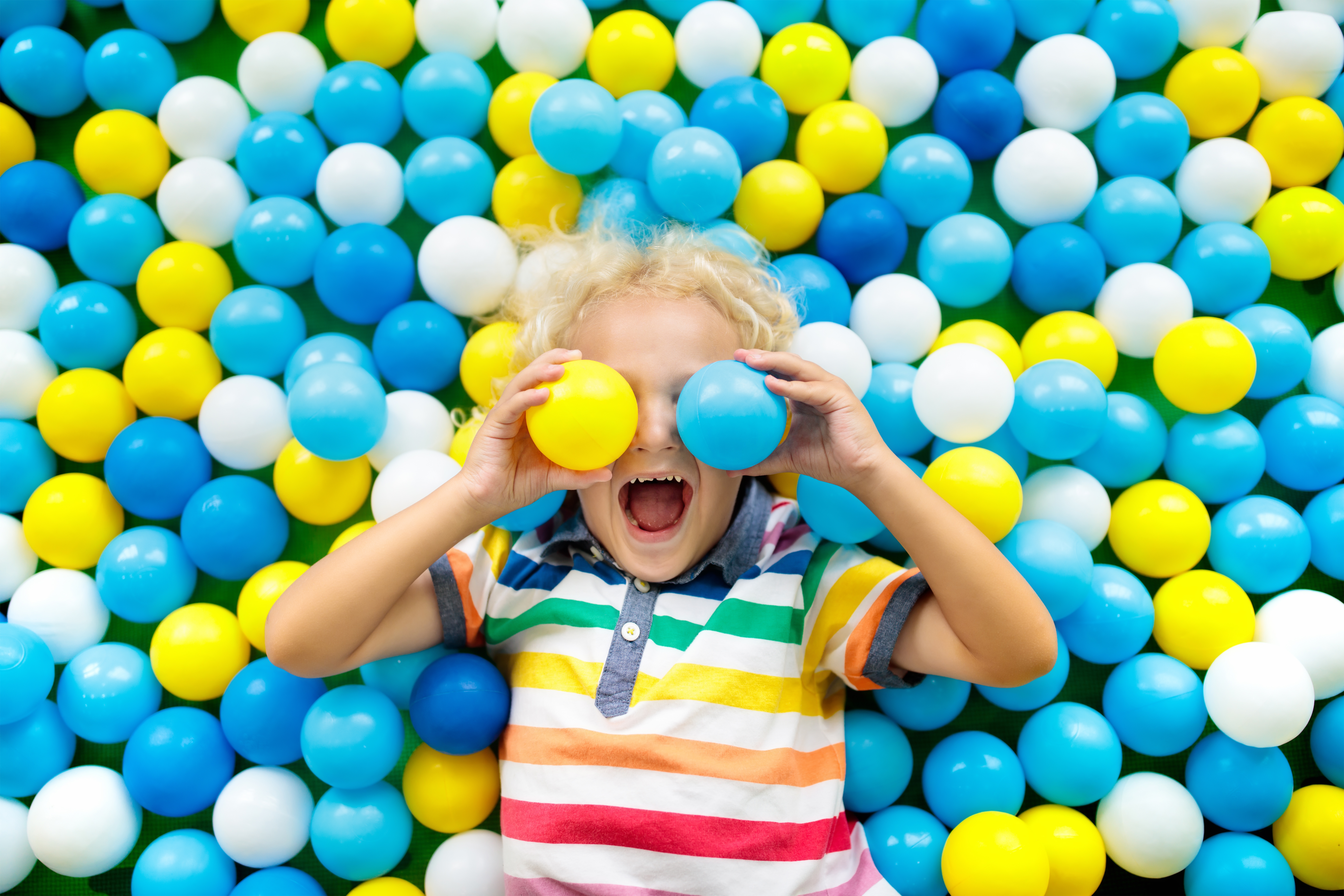 Child playing in ball pit. Colorful toys for kids. Kindergarten or preschool play room. Toddler kid at day care indoor playground. Balls pool for children. Birthday party for active preschooler.